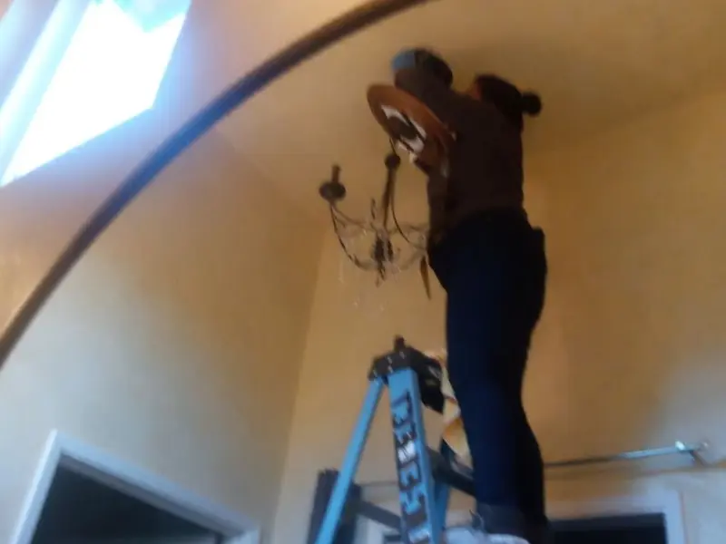 Electrician installing a chandelier in a Boxford residence